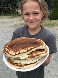 boy holding a plate of pancakes at the campground