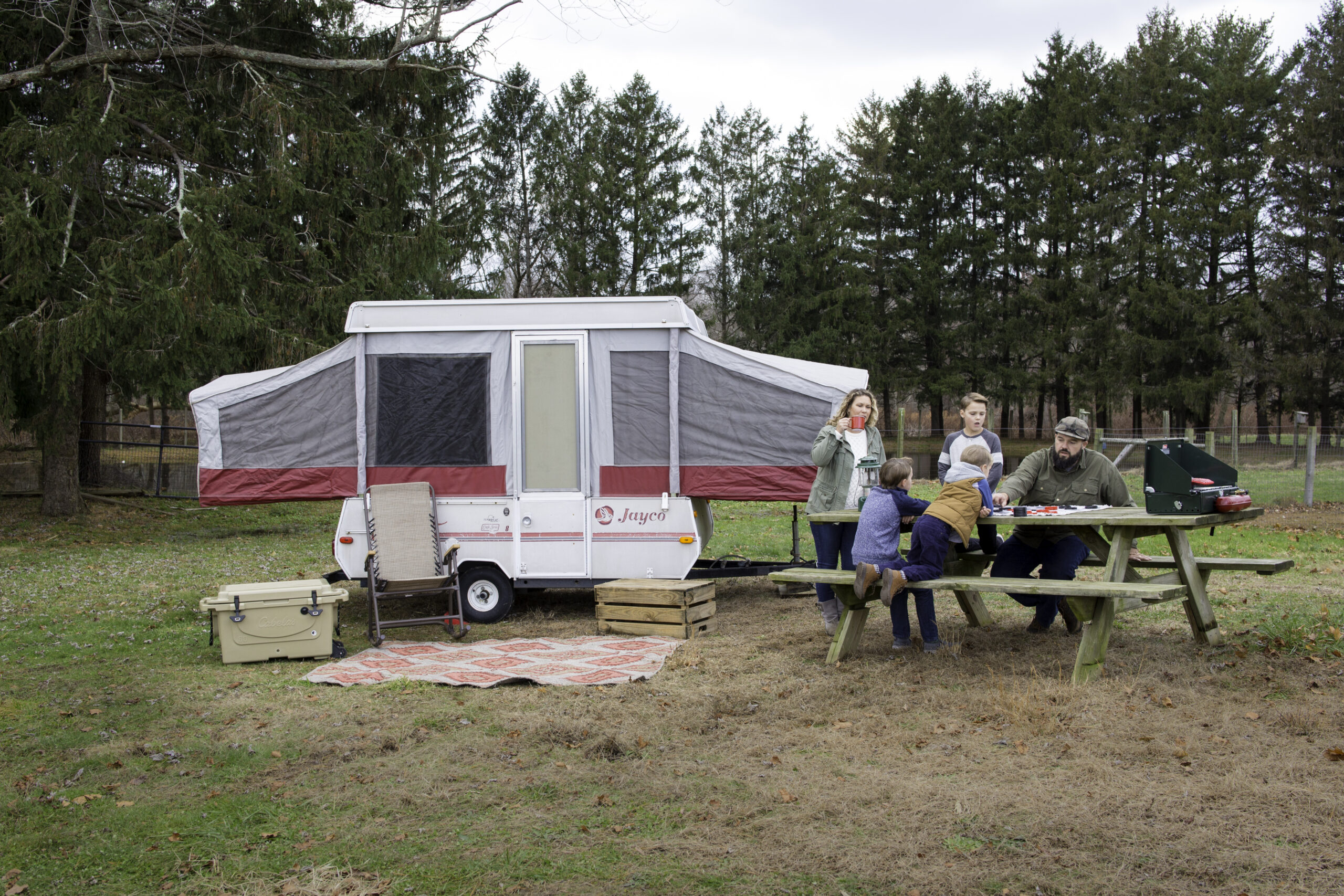 A family in front of a pop up camper at the campground